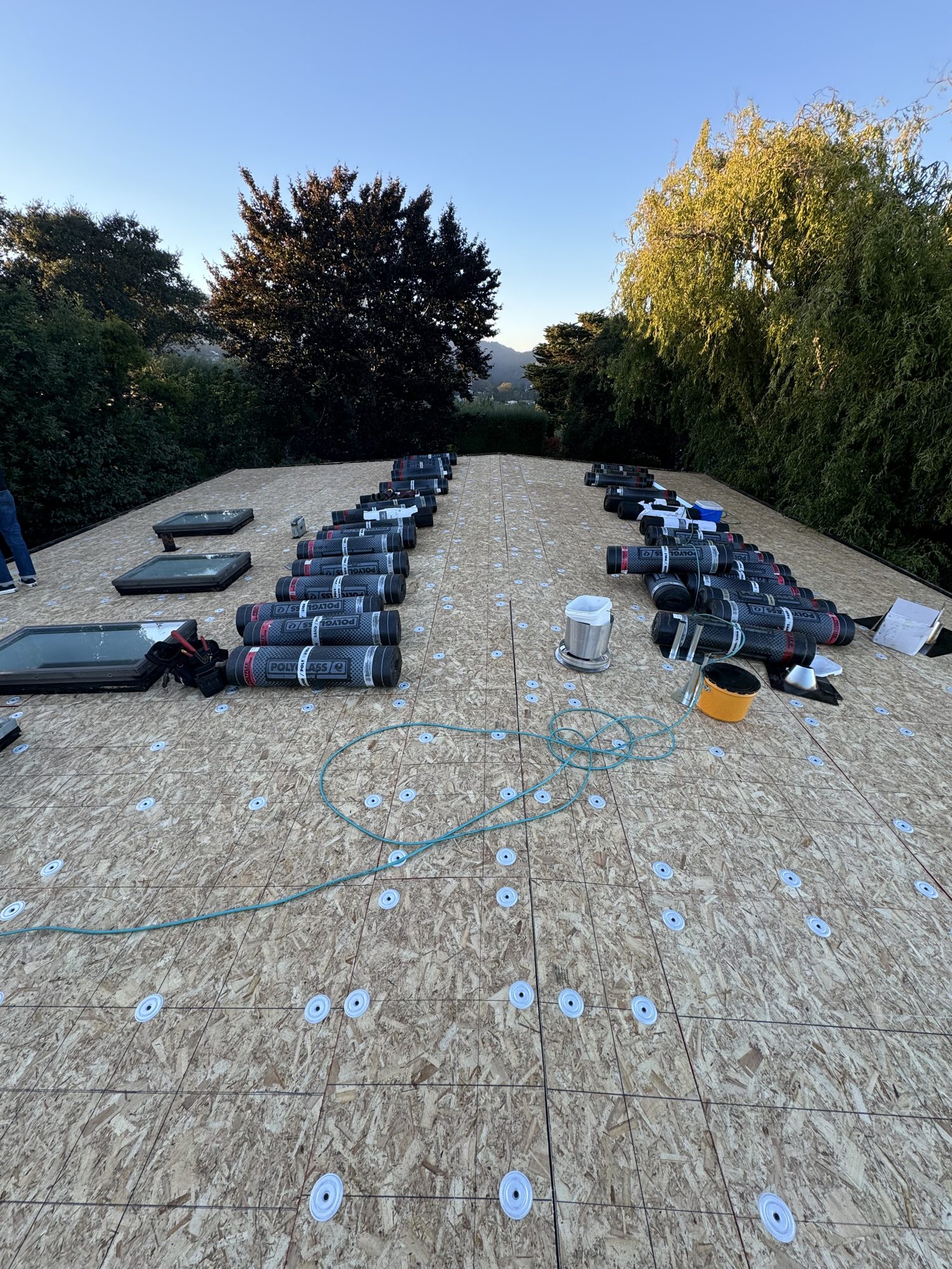 Flat roof deck prepared with new underlayment rolls on a San Jose project