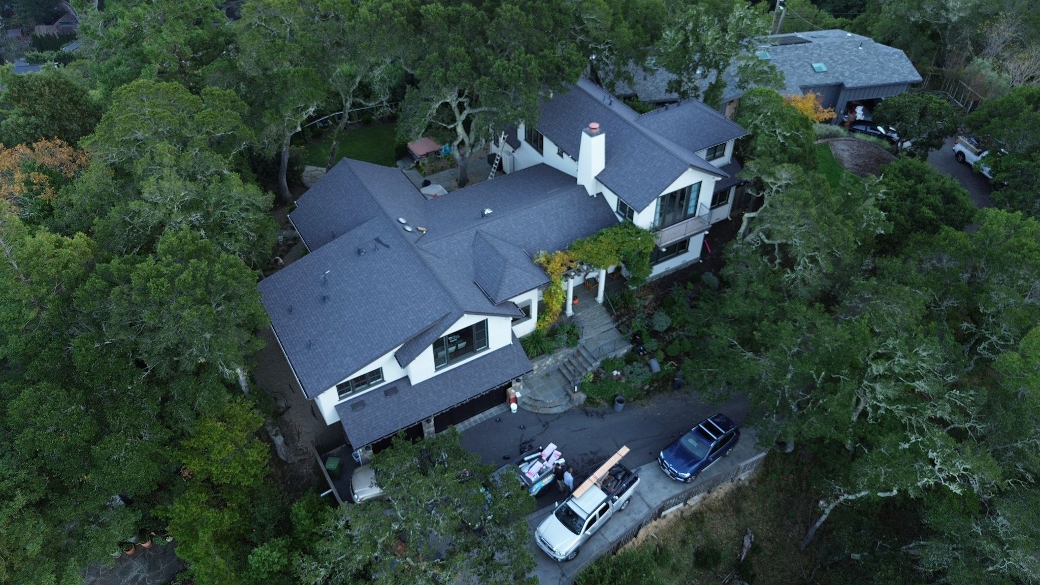 Professional roofer in safety harness working on a steep residential roof at sunset